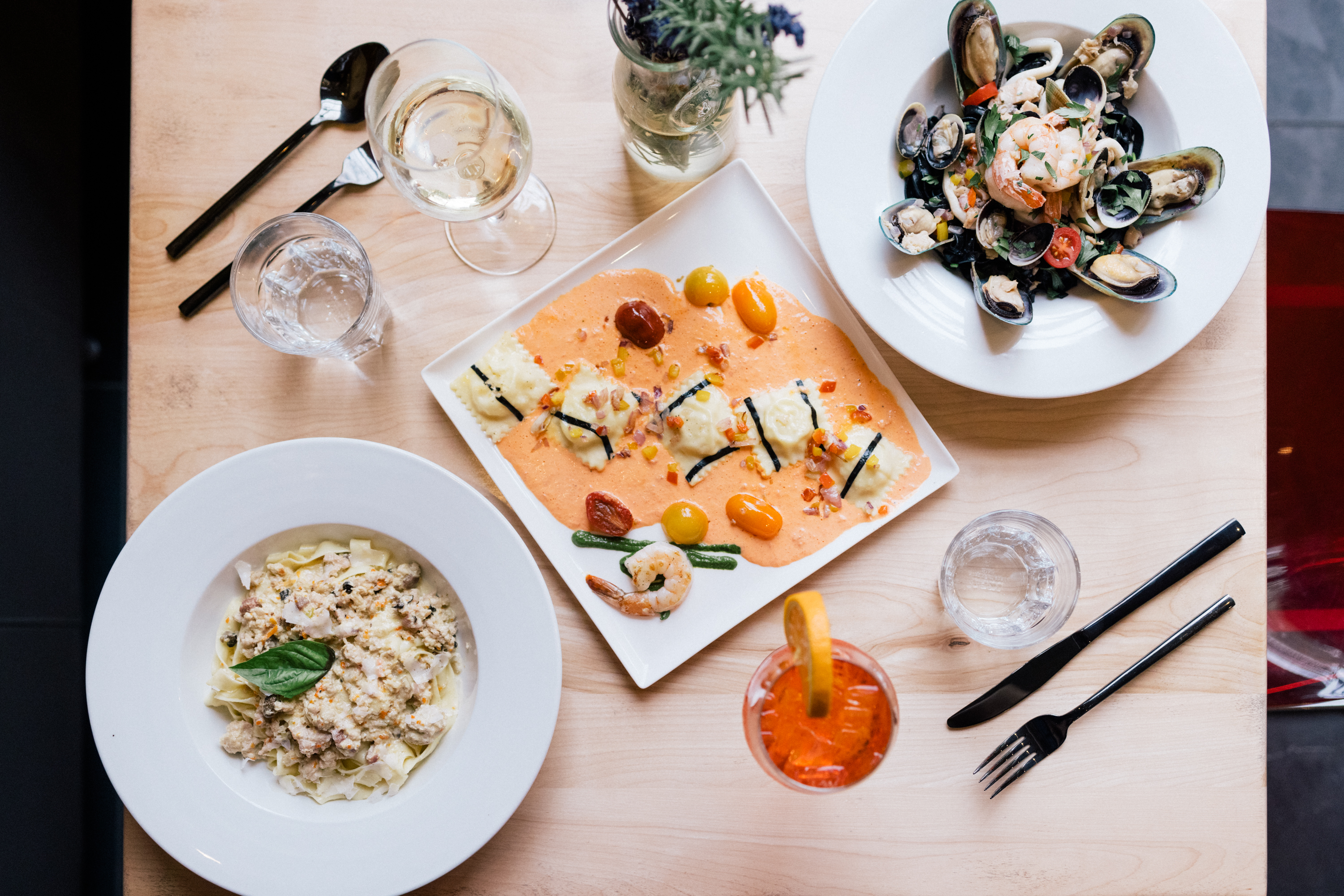 Ravioli, tagliatelle and squid-ink seafood pasta on a table
