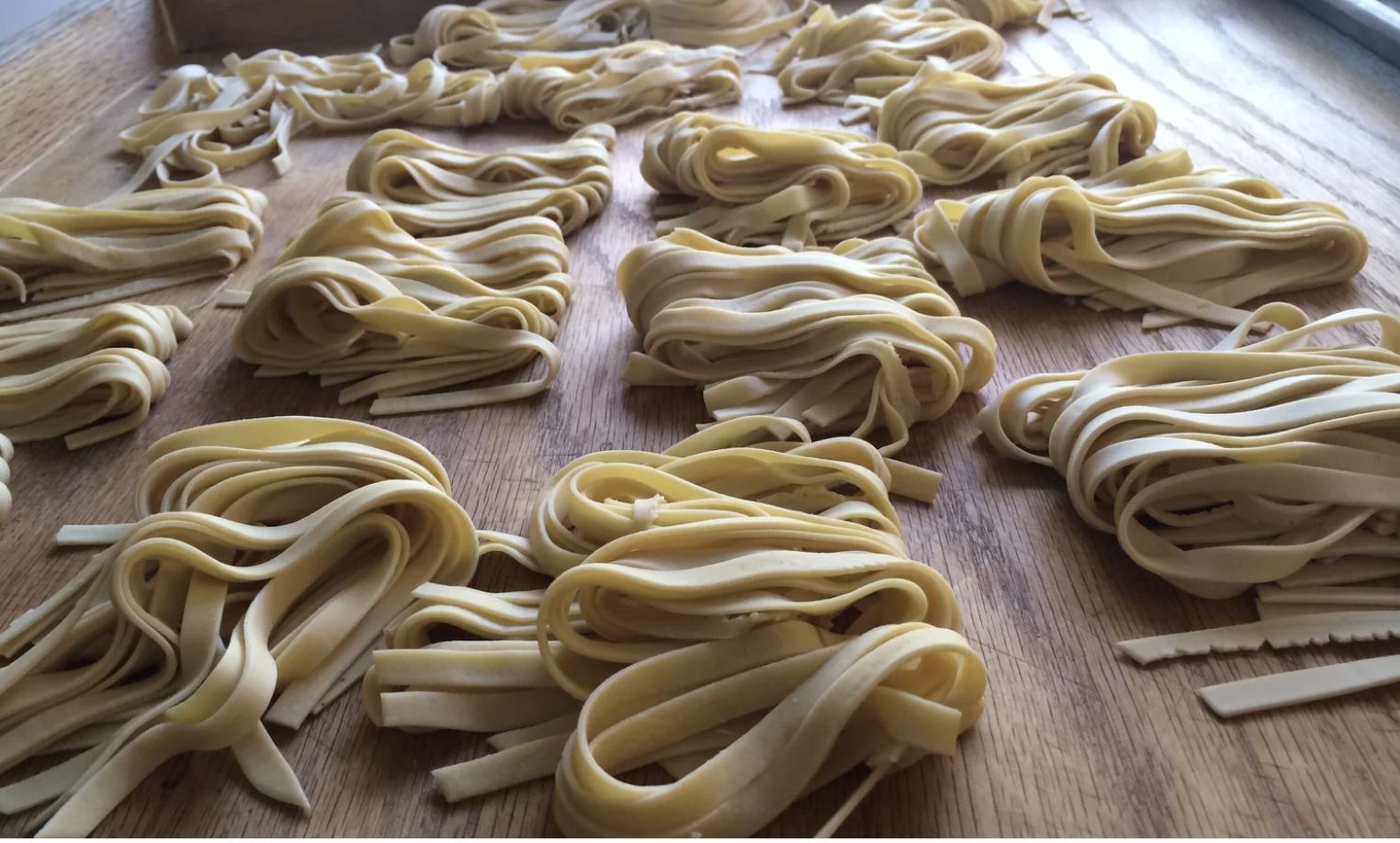 Nests of fresh tagliatelle drying on a wooden board